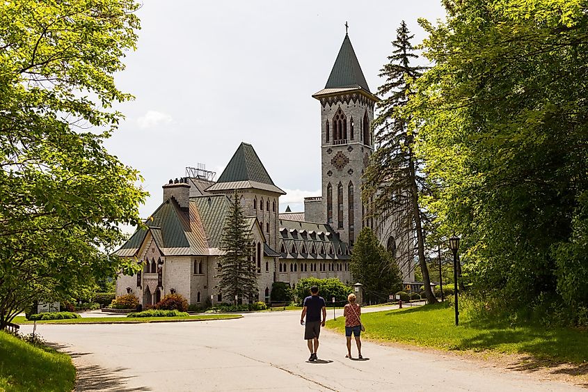 Couple walking towards the 40s Saint-Benoît-du-Lac Abbey in the Estrie region in late spring