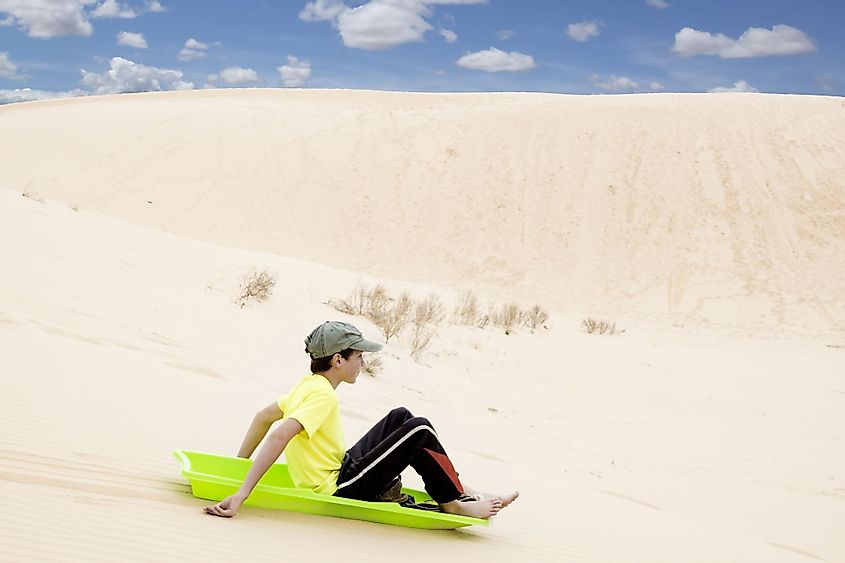 A child on a sled pulls off the sandy mountains in Monahans Sandhills State Park, Texas
