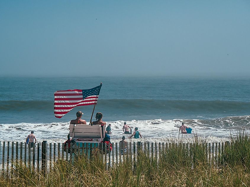 People and lifeguard stand with US flag at Rehoboth Beach, Delaware.