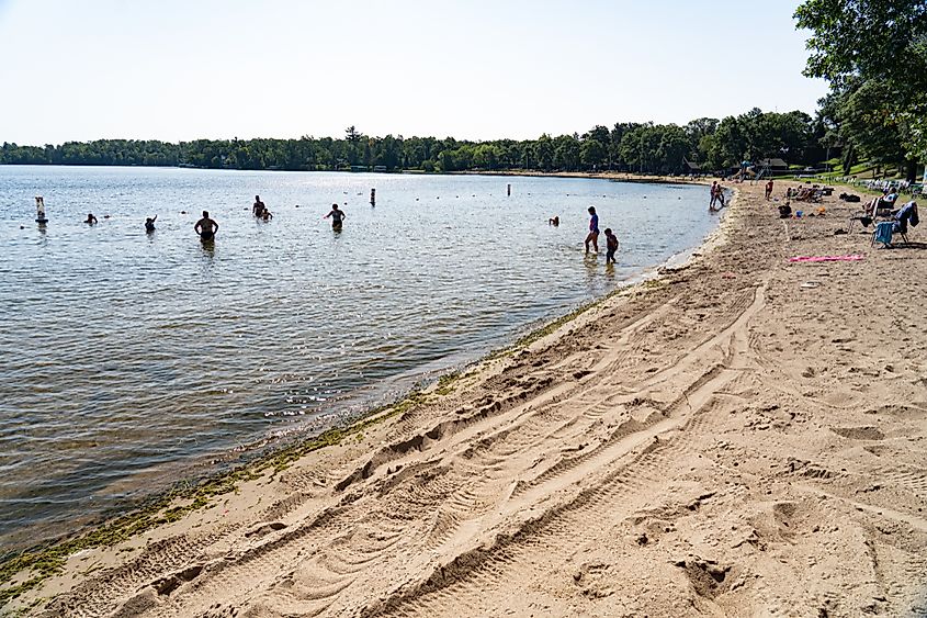 Vistitors and families enjoy the water on the shores of Gull Lake on a beautiful, summer day, via Stephen Reeves / Shutterstock.com