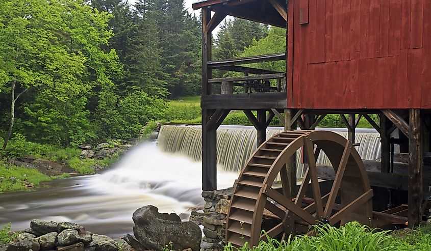 Water pours over a dam next to an old red mill near the Weston Playhouse in Weston, Vermont