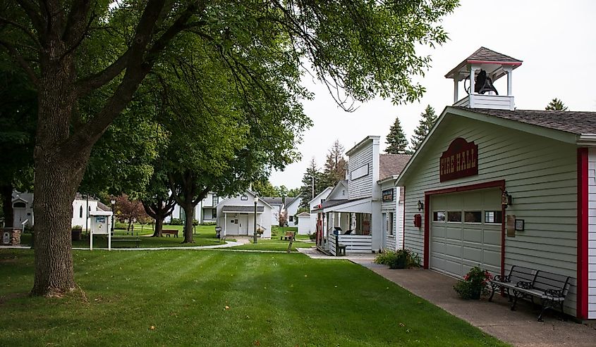 Owatonna, Minnesota, Colonial buildings at county fairgrounds. White buildings, green grass and large leafy trees.