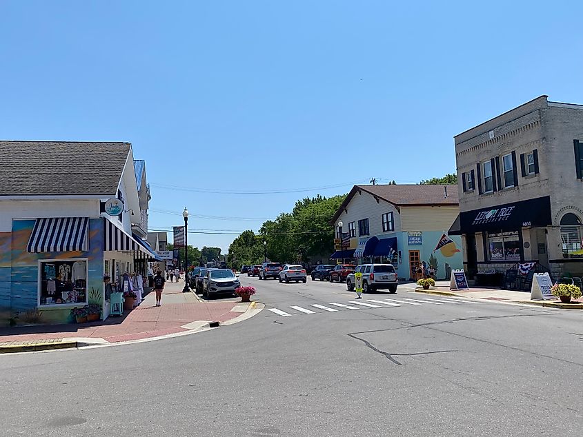 A small town intersection where the little shops have colorful murals outside of them.