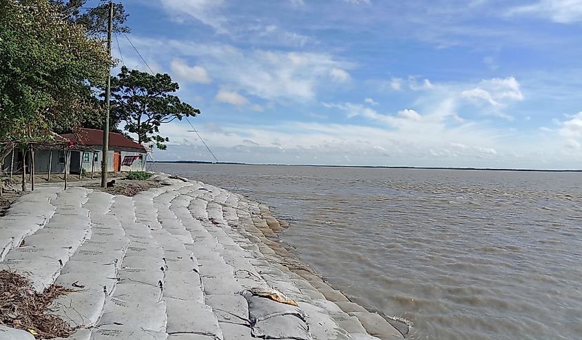 Rural Bangladesh with Jamuna River shore and little building outside.