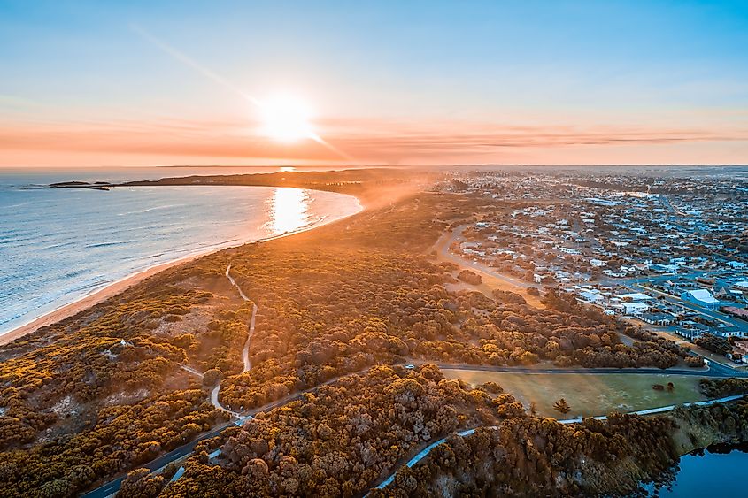 Sunset with sun flare over Warrnambool town and ocean in Australia.