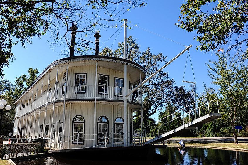 Double-decker paddle boat serving as a visitor's center for Greenville, Mississippi. The boat, white with black trim, floats gracefully on the water, offering a unique and inviting welcome to visitors.