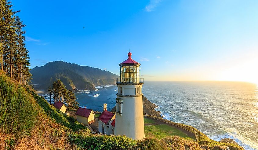 The sun sets in the sea and illuminates Heceta Head Lighthouse, Oregon