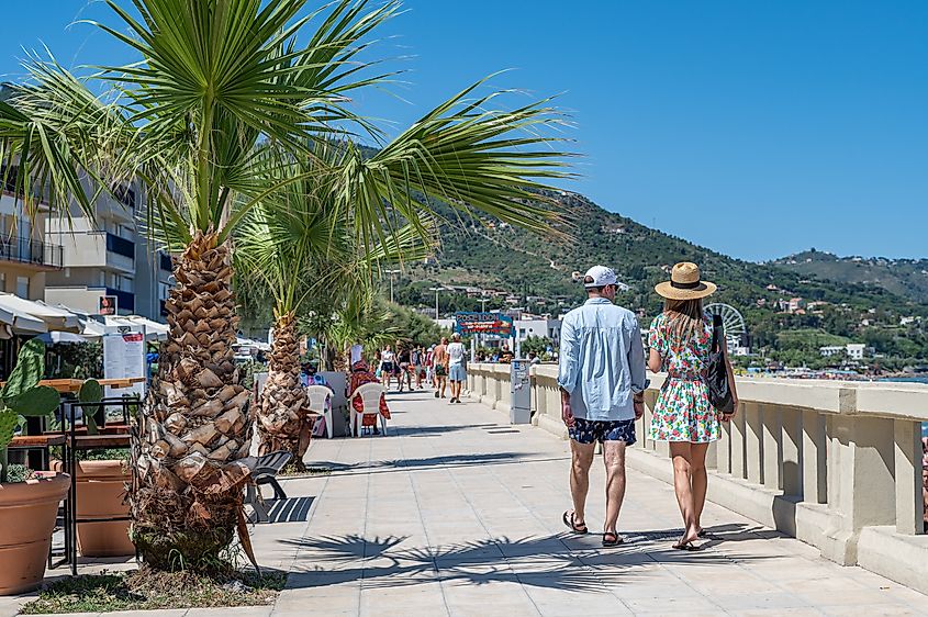 People enjoying beachside strolls in Cefalù, Italy.