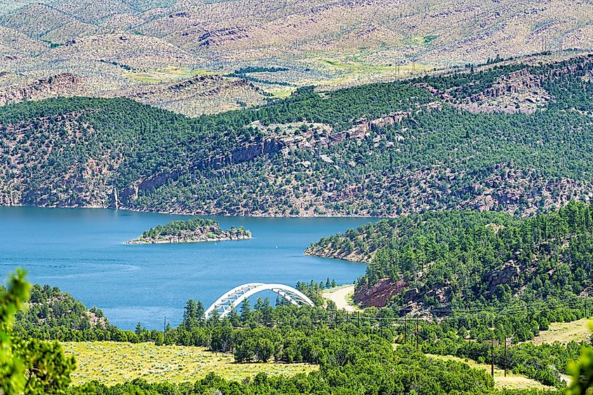 Aerial view of the Flaming Gorge Reservoir Bridge and green hills in Dutch John, Utah.