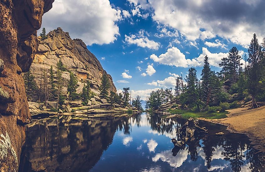 Perfectly still water on Gem Lake with reflection of blue sky, clouds, mountains, and trees, Estes Park, Colorado