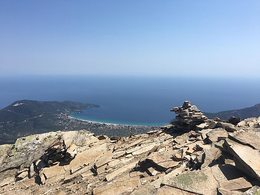 The summit of a sun-soaked mountain, overlooking a small beach town far below. 