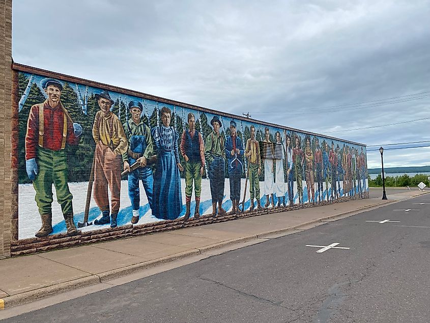 A mural depicting early settlers spans the entire side of a brick building.