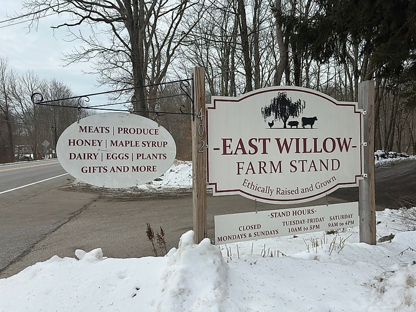 Columbia, Connecticut, USA - February 15, 2025: Sign for East Willow Farm Stand. Winter outdoor scene. Hours and products listed: meats, produce, honey, maple syrup, dairy, eggs, plants, gifts. Rachel Rose Boucher via Shutterstock