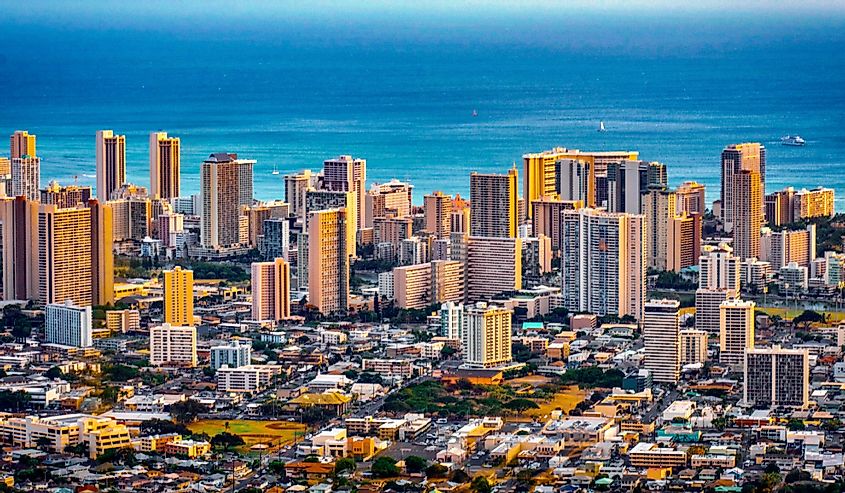 Cityscape of Honolulu city and Waikiki beach with blue ocean and light reflection from sunset sky to buildings from Ualaka’a lookout on Tantalus mountain