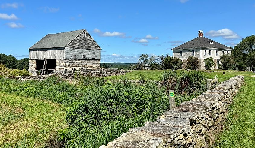 Two buildings at Buttonwood Farm with stone wall in Griswold, Connecticut.