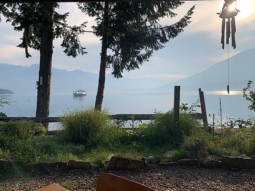 A passenger ferry approaches a sunny and misty shore.