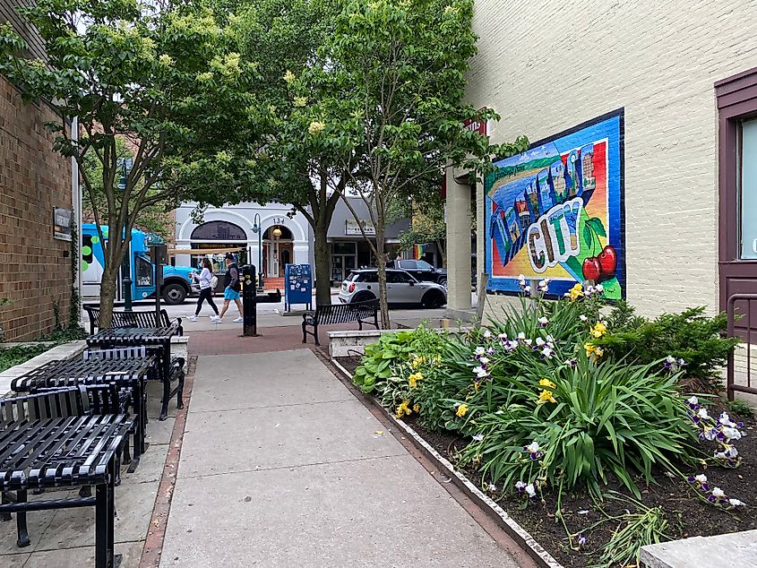 Looking up a decorated, nature-infused alleyway toward a small town Main Street.