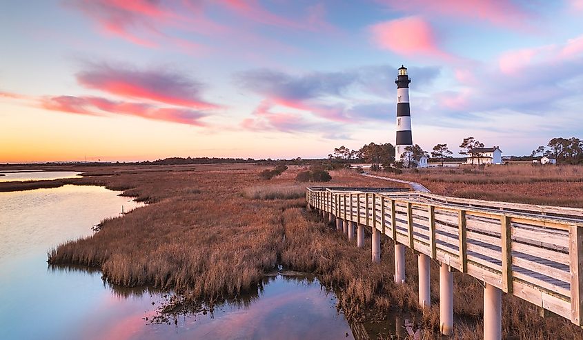 Clouds stream like pink ribbons in the sky over the marsh and lighthouse on Bodie Island on the Outer Banks of North Carolina.