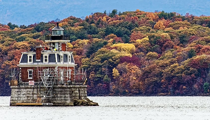 Hudson-Athens Lighthouse on the Hudson River viewed from Hudson, New York, with autumn foliage and the Catskill Mountains in the background.
