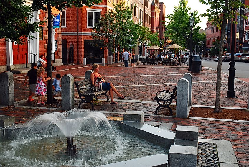 A family enjoys a lovely summer afternoon near a fountain, sitting on a bench in downtown Portsmouth, New Hampshire
