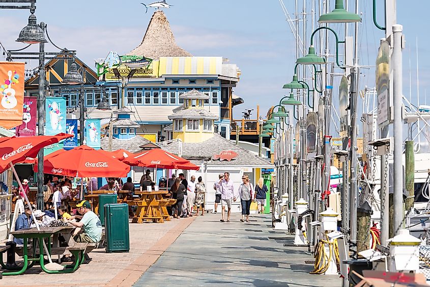 Harborwalk village city town with boardwalk at marina, people sitting eating outside at restaurant cafe on summer day in Florida Panhandle, Gulf of Mexico, via Andriy Blokhin / Shutterstock.com