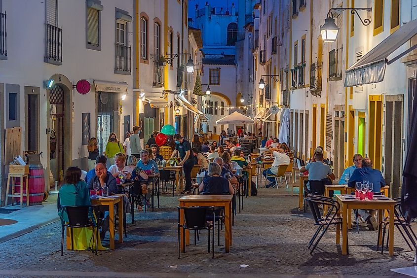People are having dinner on a street in Evora, Portugal.