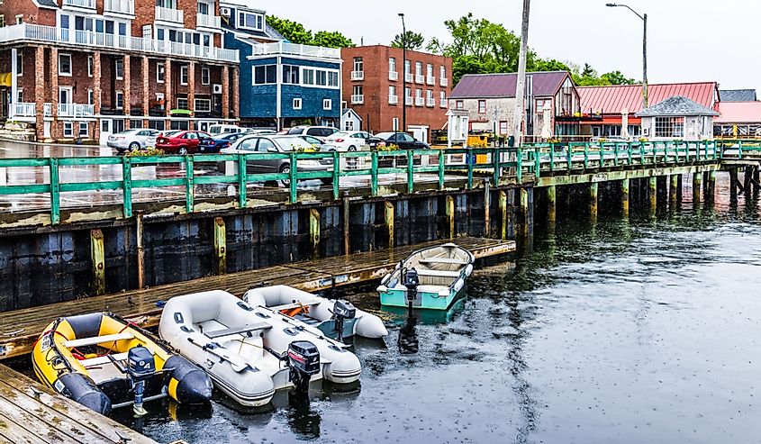 Empty wooden marina harbor in Castine, Maine during rain with boats and parking lot