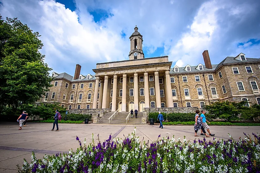 Students and adults walk in front of the Old Main building at Penn State University.