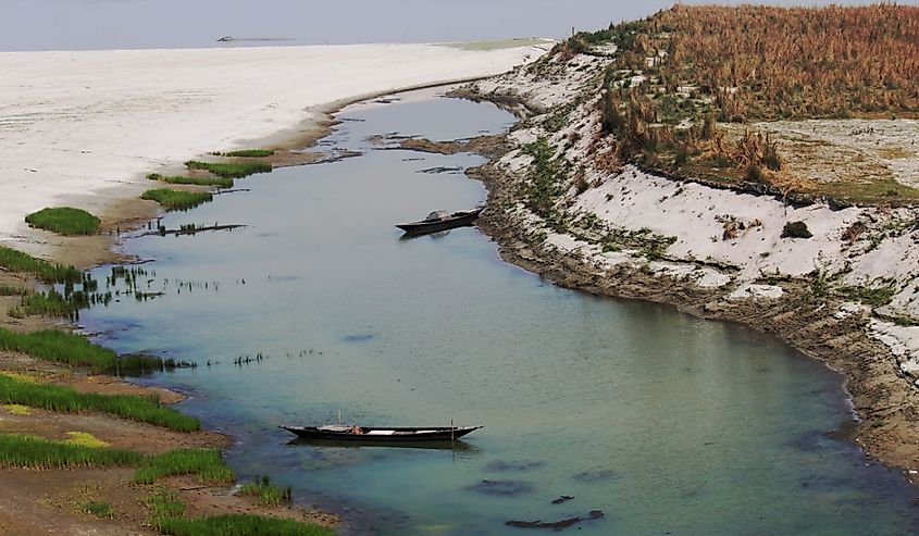 Jamuna river flows with greenery to the right and snowy ground to the left. 