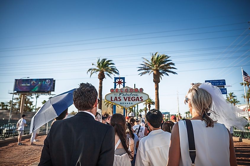 A couple in wedding attire, wait in line to take photos at the Welcome to Fabulous Las Vegas sign.