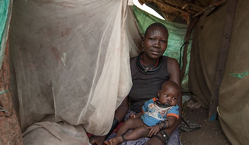Unidentified woman with baby sits in makeshift hovel in displaced persons camp, Juba, South Sudan. Refugees stay in harsh conditions in camps of Juba., South Sudan