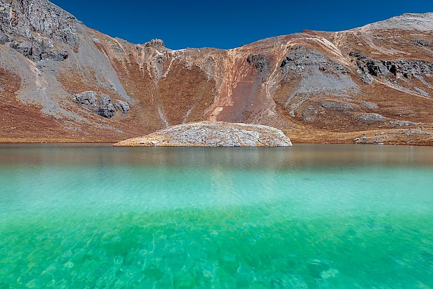 Island Lake, nestled at 12,390 feet in the Ice Lakes Basin near Silverton, Colorado, features striking emerald-green to vibrant turquoise water.