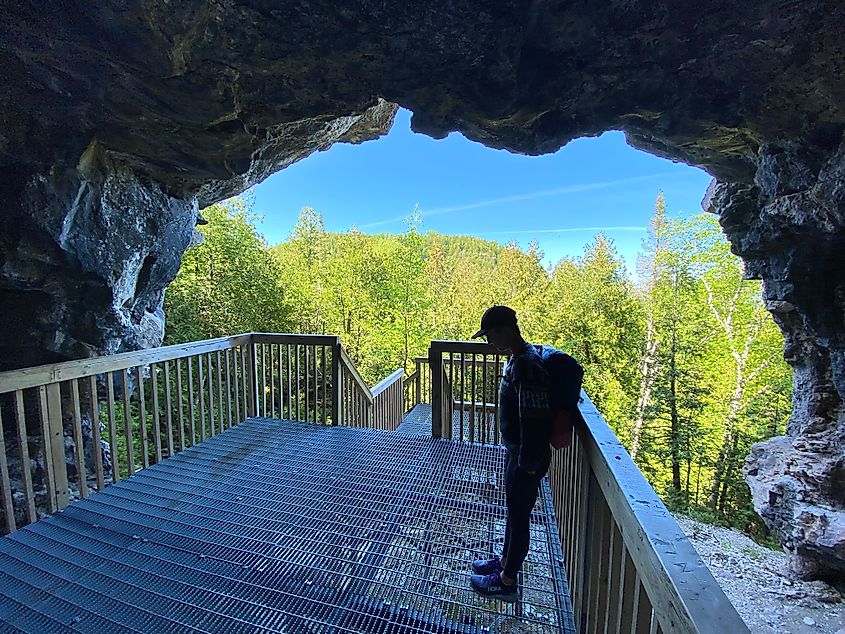 A woman stands on an artificial platform within an elevated limestone cave 