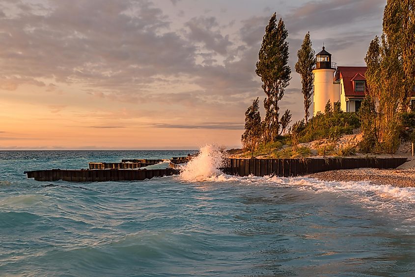 Waves crash along the Lake Michigan shore in front of Point Betsie Lighthouse, during sunset