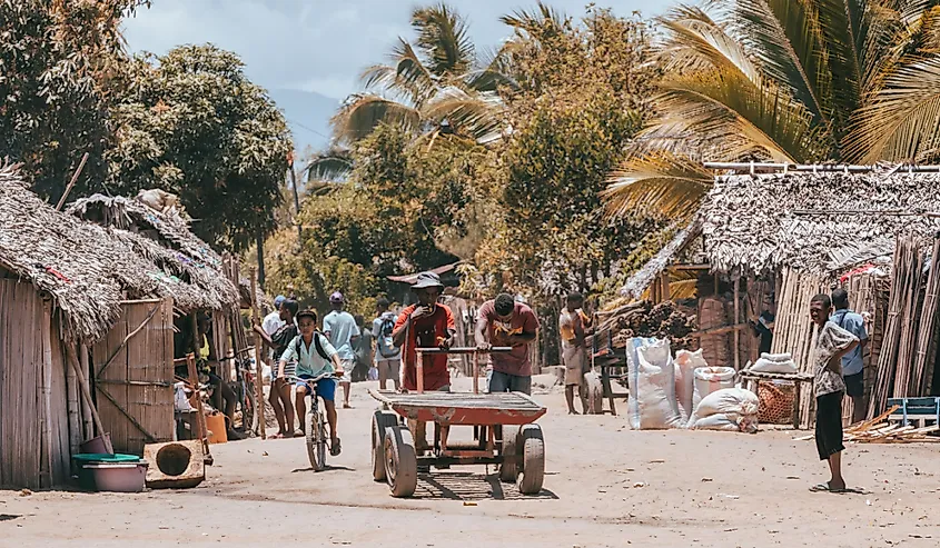 Two Malagasy young men pushing a wagon on marketplace street. Daily life in Madagascar