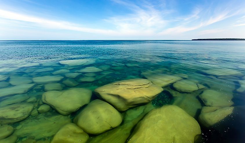 The clear waters of Lake Superior reveal large rocks and stones underwater.