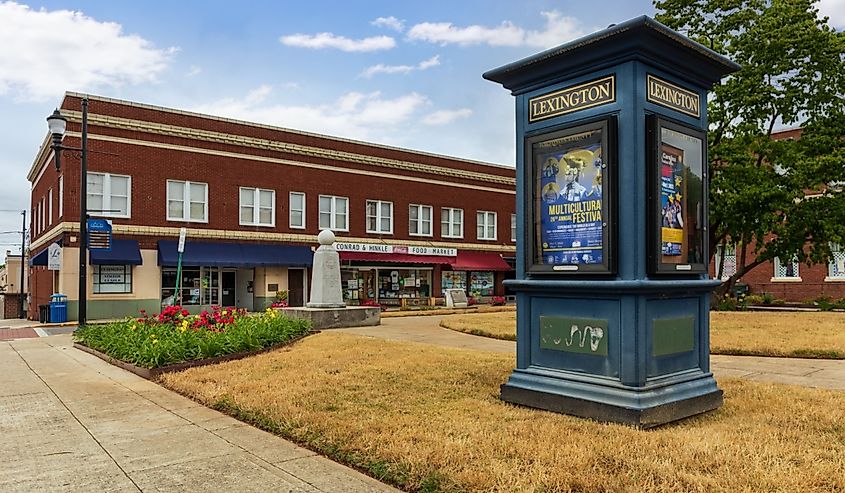 Kiosk showing informational posters of cultural events sets in front of vintage buildings and businesse