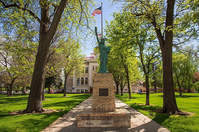 Sterling, Colorado. Sterling city hall and Statue of Liberty with tree lined sidewalk.