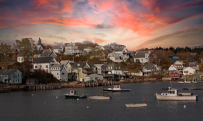 Lobster boats at anchor with bayfront homes in Stonington, Maine, USA.