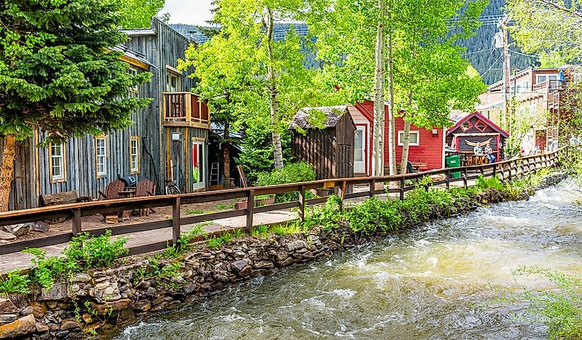 Colorado village houses by coal creek river in summer with vintage mountain architecture and aspen trees on sunny day in Crested Butte