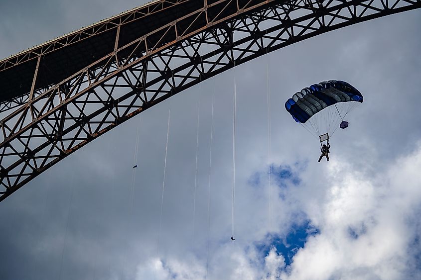 BASE jumper flying parachute under the New River Gorge Bridge in West Virginia during Bridge Day. Credit: Flying Pig Studios/Shutterstock.com