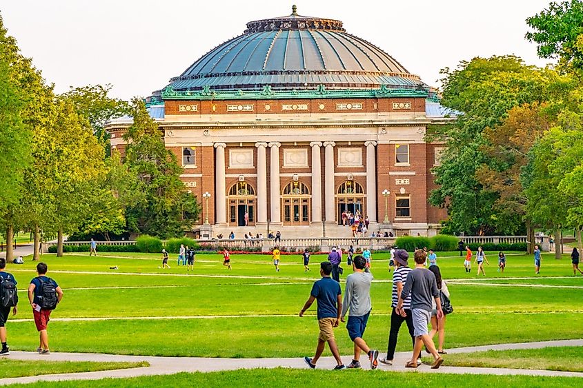 Students walk outdoors on lawn of University of Illinois college campus quad in Urbana Champaign Illinois