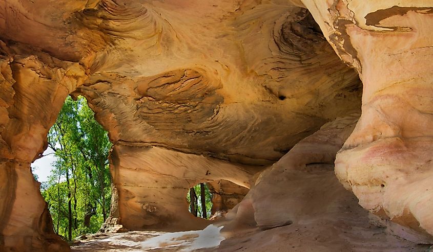 Views of the forest through an archway from inside sandstone caves in Pilliga Nature Reserve, New South Wales, Australia.