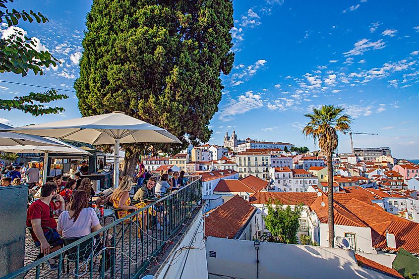 Street cafe with tables outside and people sitting and having food, Lisbon, Portugal