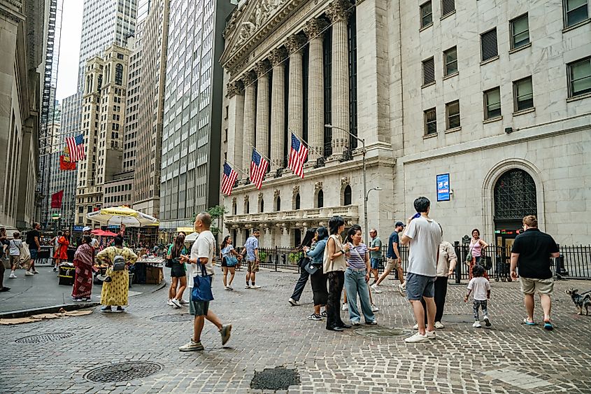 Crowds of tourists walk along Wall Street in New York City financial district