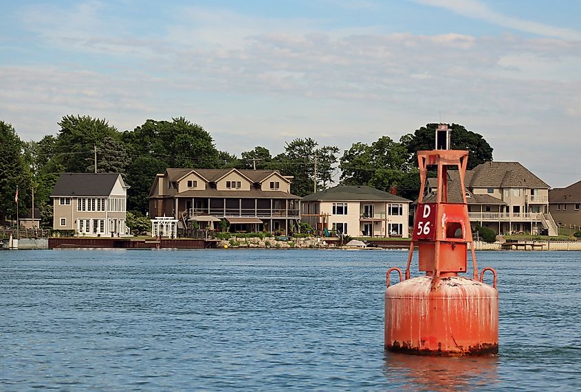 Editorial Photo Credit: Barbara Kalbfleisch via Shutterstock. Amherstburg, ONT, CA: June 19, 2018 - Channel Marker D56 in foreground. Riverfront homes in Amherstburg in background. Red channel markers are even numbered, Green markers are odd numbered.