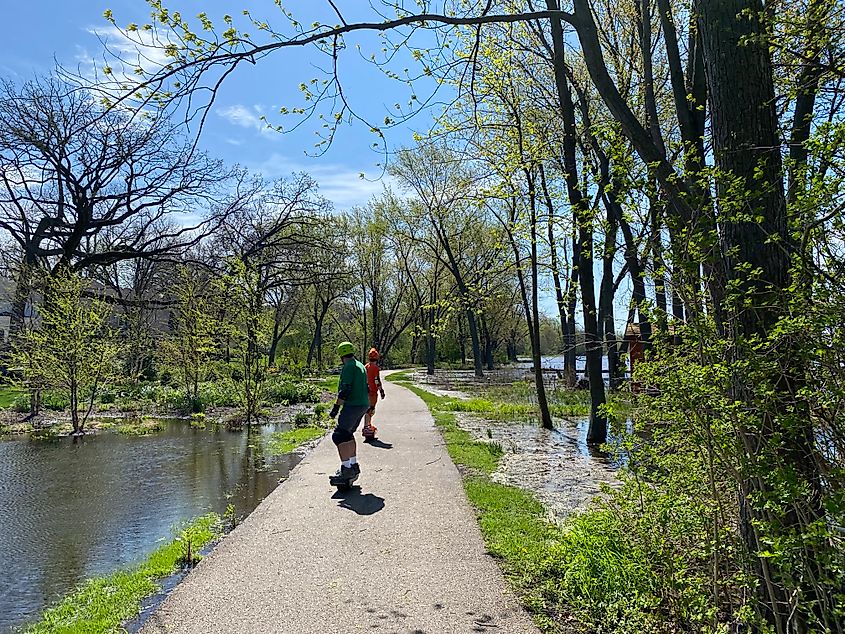 Two skateboarders cruise along a paved river path.