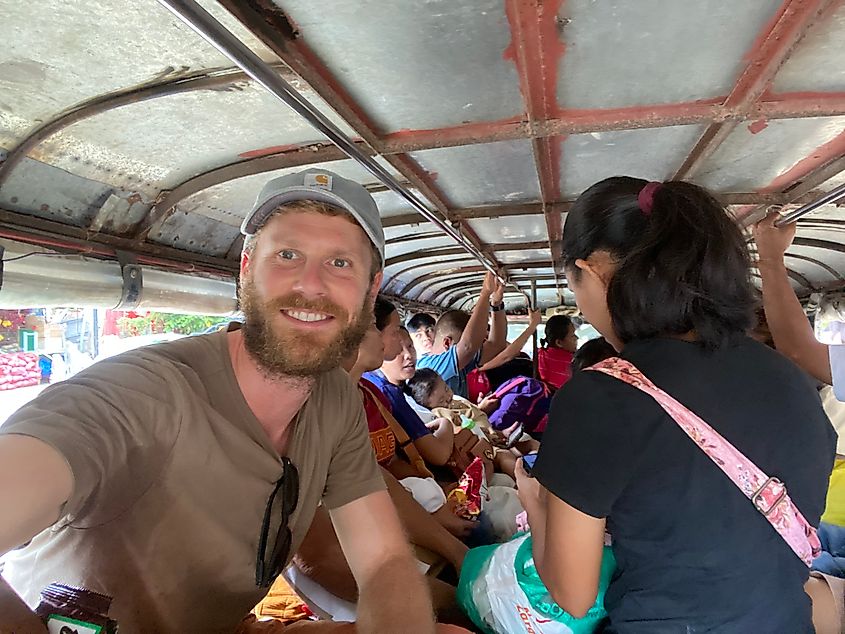 A male traveler takes a selfie aboard a cramped, open-air Jeepney in the rural Philippines.