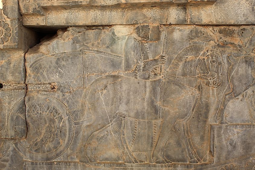 Achaemenid soldiers with spears in hand with horses and carriages carved on the ancient stones of Persepolis.