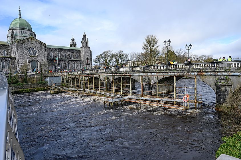 Galway Cathedral on the banks of River Corrib, Galway, the Salmon Weir Bridge over the river.